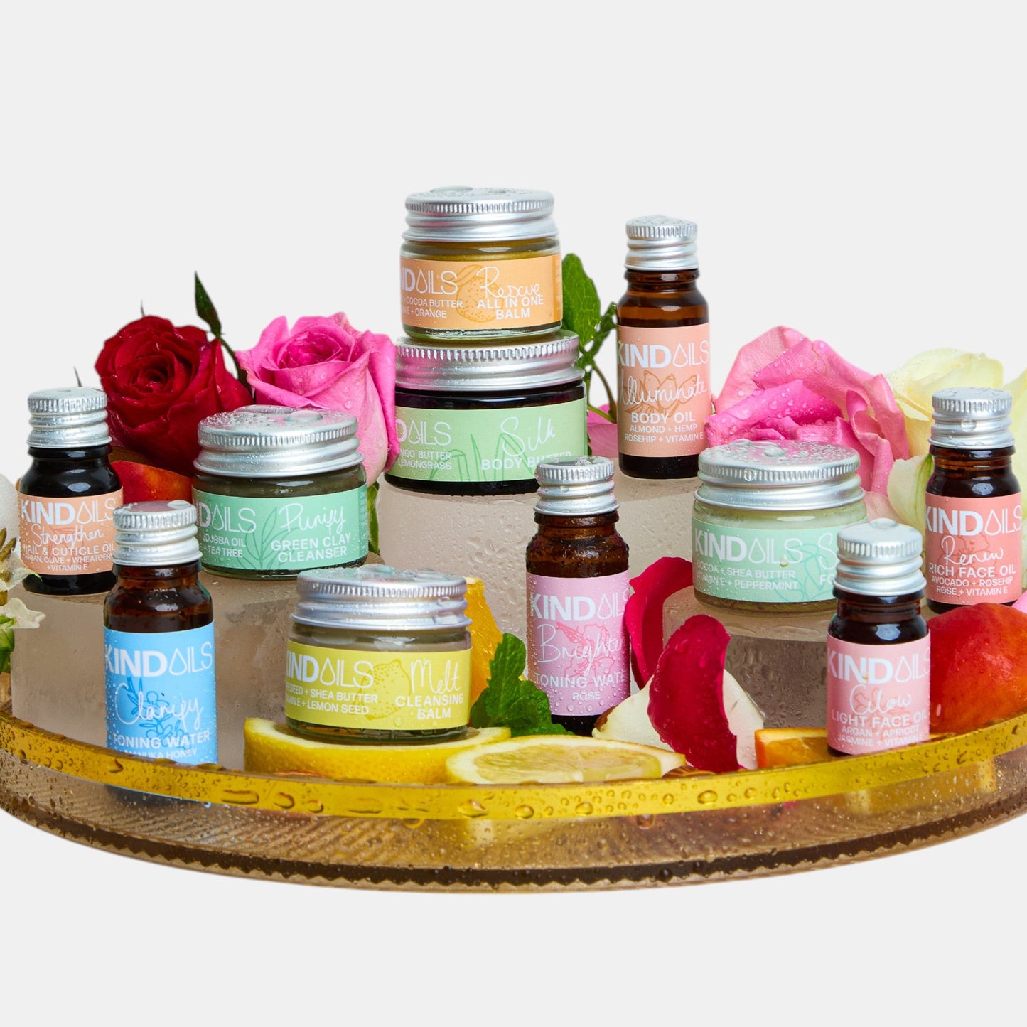 Collection of small bottles and jars on a decorative tray with flowers on a white background