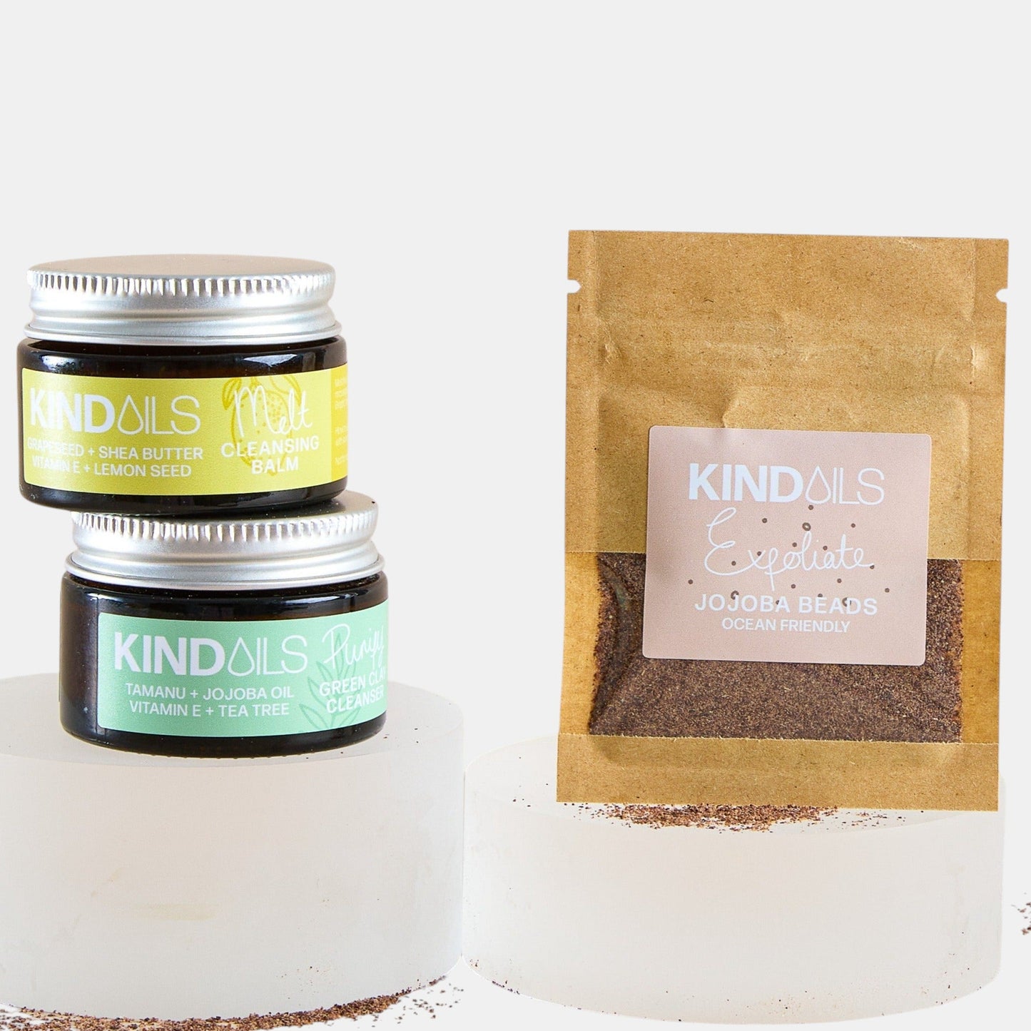 Two jars and a brown paper bag with kind oils branding on a white background.