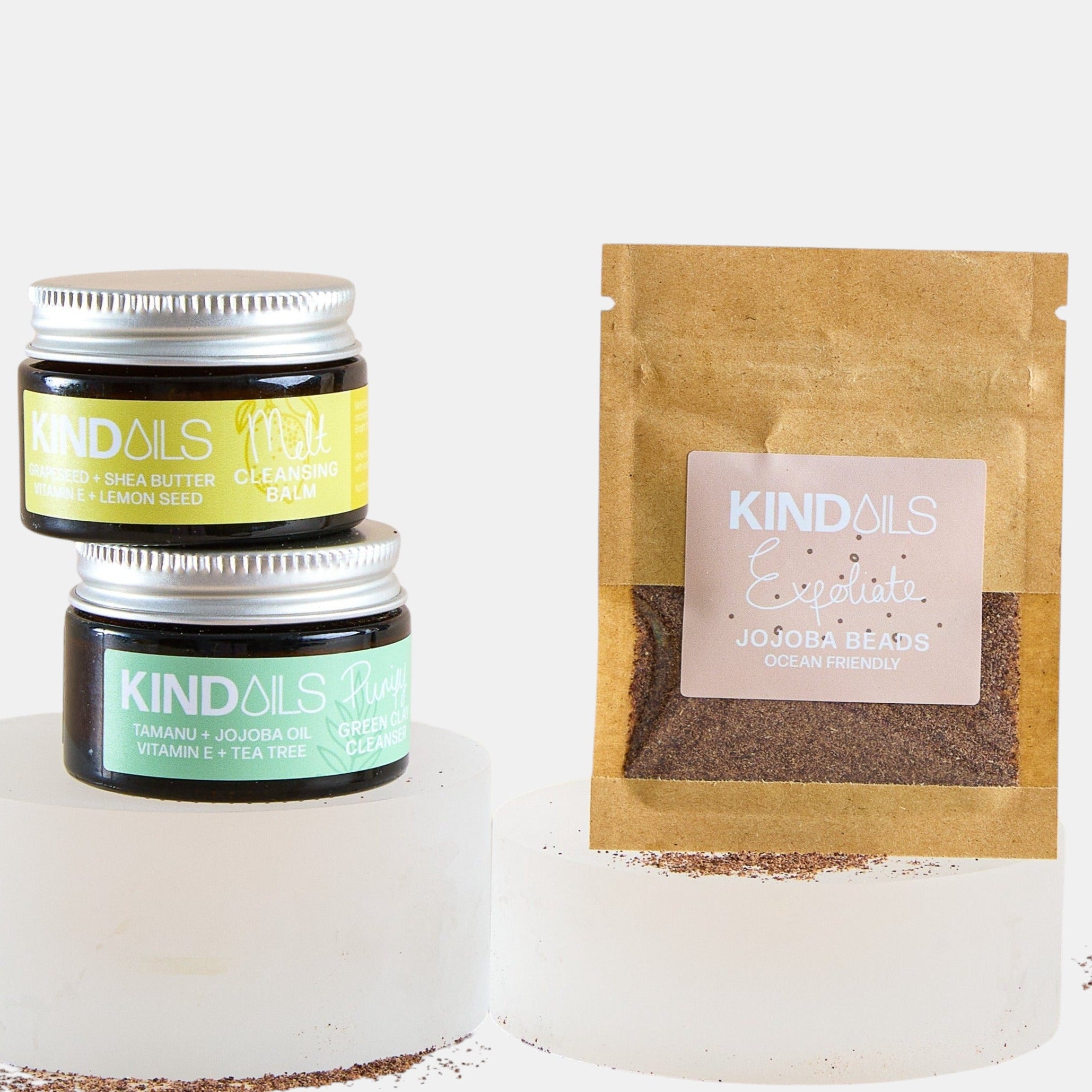 Two jars and a brown paper bag with kind oils branding on a white background.