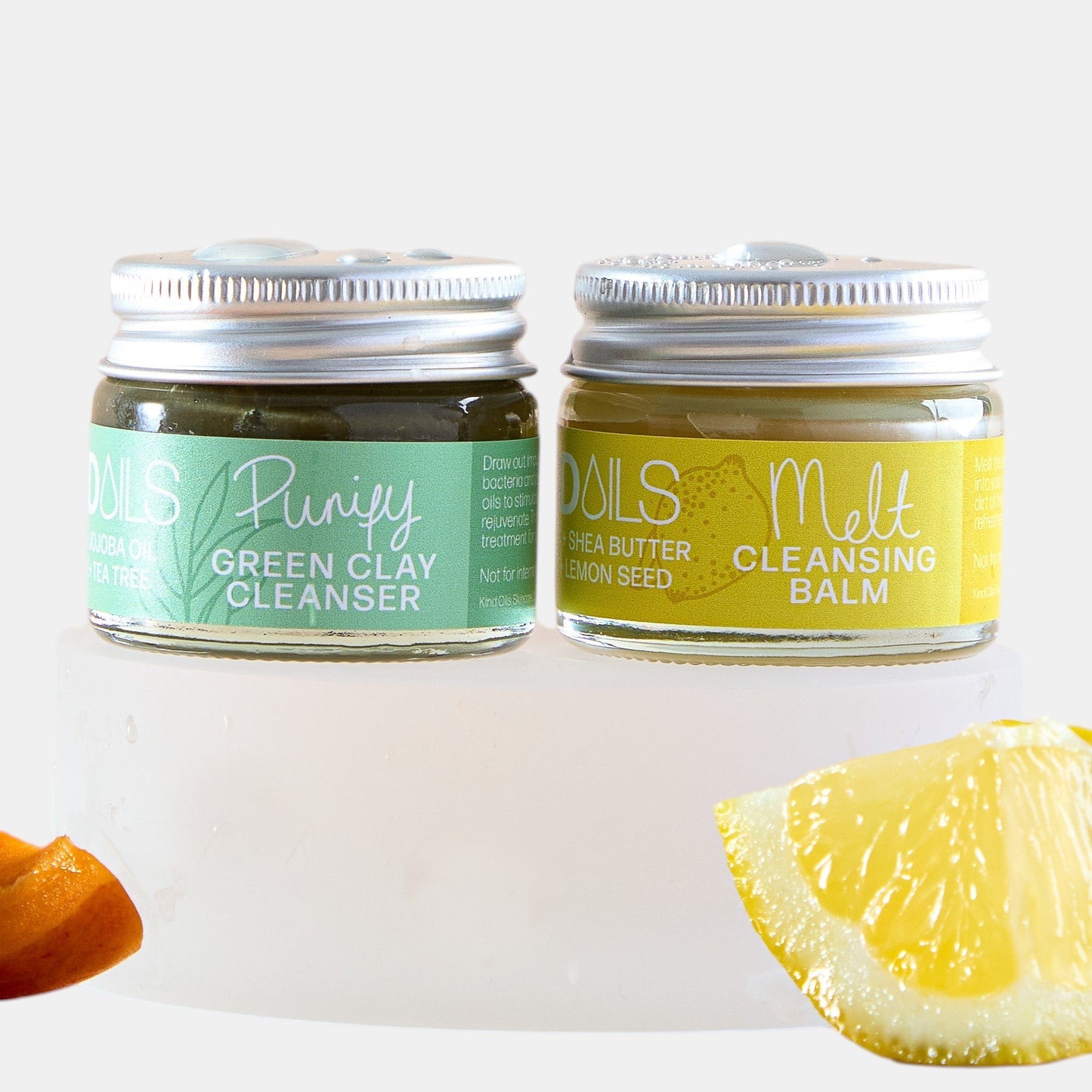 Two jars of skincare products with a lemon and orange on a white background